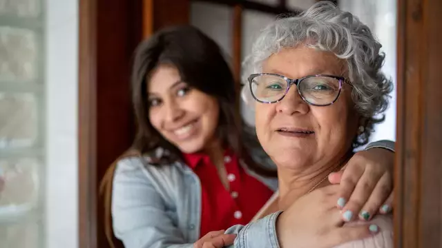Mujer mayor con un cuidador abrazándola.​​ 